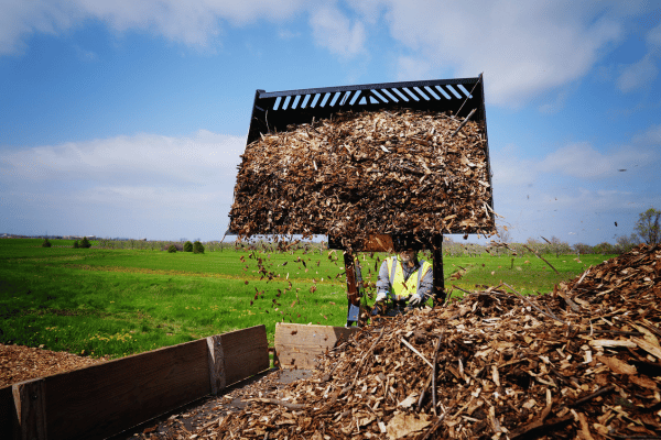 Vermeer Mini Skid Steer with bucket attachment lifting mulch into truck bed